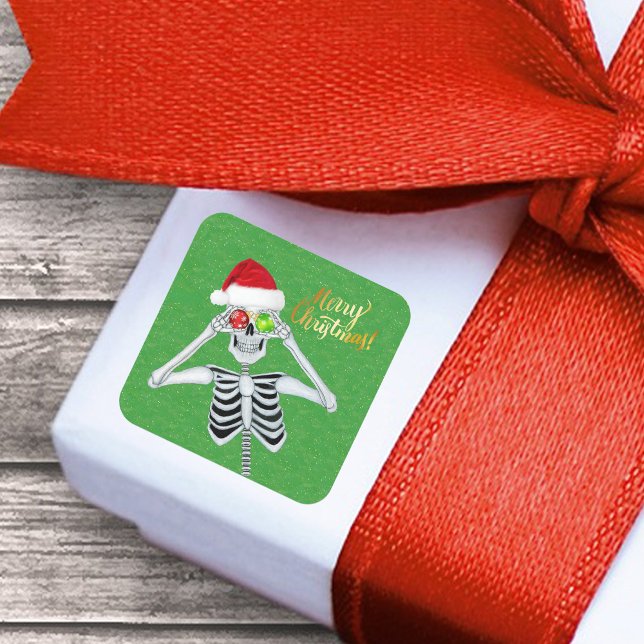 Adesivo Quadrado Sorriso de Natal Olhos de Ornamento de Esqueleto e (Funny Merry Christmas Skeleton ornament eyes Santa Hat on green with gold flecks paper sticker.)