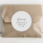 Adesivo Redondo Espanhol Simples Obrigado Favor De Casamento<br><div class="desc">Este simples obrigado espanhol que o teu casamento a favor de um adesivo redondo clássico é perfeito para um casamento moderno. O design simples e elegante apresenta a tipografia de scripts clássicos e ricos em preto e branco. Faça com que a etiqueta do adesivo seja sua, incluindo seus nomes, o...</div>