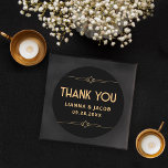 Adesivo Redondo Obrigado Arte Moderna Deco Negra e Dourado Casamen<br><div class="desc">O Clássico Arte Moderna Deco Preto e Dourado Casamento é a maneira perfeita de dizer obrigado com estilo. Apresenta um fundo preto elegante e sotaques geométricos de ouro elegantes. Ideal para selar envelopes ou adicionar um toque pessoal aos seus favores, este adesivo captura a sofisticação do design de Arte moderna....</div>