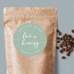 Adesivo Redondo Relax Script Love está criando casamento de cores<br><div class="desc">Vinheta de casamento com as palavras "Love is Brewing" em um texto cursivo relaxado em branco contra uma cor de fundo editável (clique em personalizar para acessar). Personalize-o substituindo o texto do marcador de posição. Para obter mais opções, como alterar a fonte e seu tamanho/cor, expanda a curva/contrato ou o...</div>