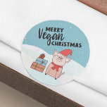 Adesivo Redondo Vegan Christmas com belos leitões e presentes<br><div class="desc">Este adesivo de Natal Vegan apresenta um belo leitão de desenho animado com um chapéu vermelho e cachecol e alguns presentes coloridos, sobre um fundo de neve. O texto negro diz "Natal Vegan da Feliz". Se precisar de ajuda, personalização adicional ou outros itens correspondentes, por favor, sinta-se à vontade para...</div>