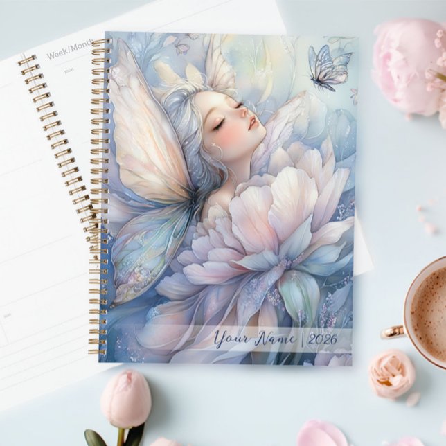 Agenda Peônia Do Amanhecer (Peony Of The Dawn planner on the table, next to a cup of coffee)