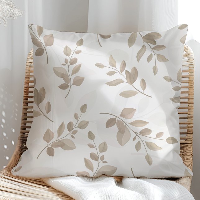 Almofada Folhas de Aquarela Bege e Branco (Beige and White Watercolor Leaves Throw Pillow in a sunny rattan armchair.)