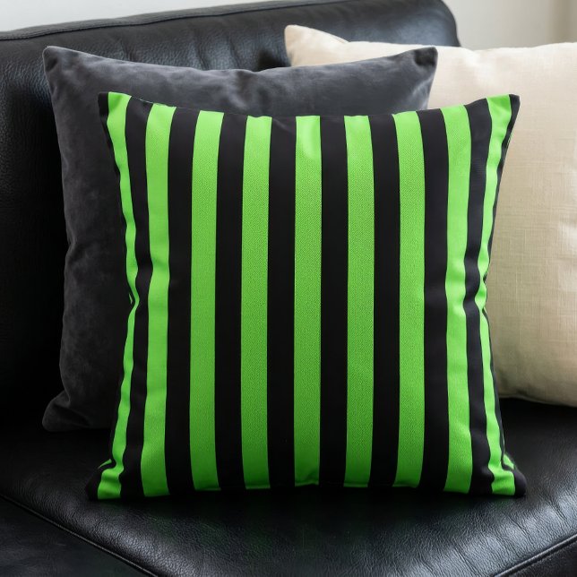Almofada Listras Pretas e Verde Lima (A lime green and black stripes pillow sits on a black couch in front of other pillows.)