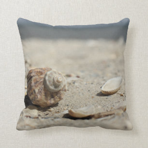Almofada Seashells na areia pelo mar