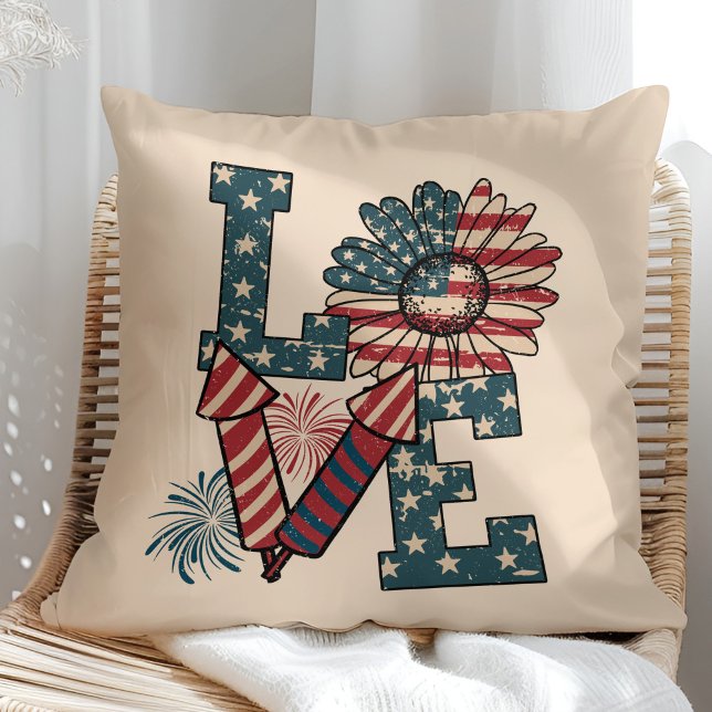 Almofada travesseiro decorativo do Dia da Independência de  ("LOVE" American Flag Independence Day Throw Pillow in a sunny rattan armchair.)