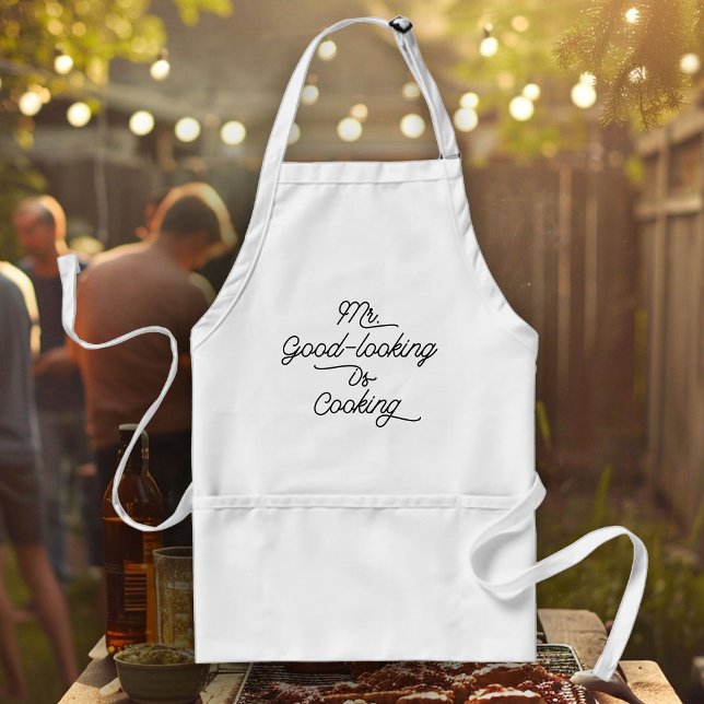 Avental Diversão Chef Humor CHURRASCO Sr. Bonito é Cozinha (White apron with "Mr. Good-looking Is Cooking" text hangs in front of a backyard barbecue)