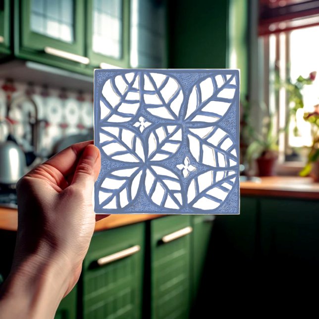 Azulejo de backsplash em cozinha, T cerâmico azul  (Blue and white ovate leaf ceramic tile held in a hand  in front of a green kitchen.)