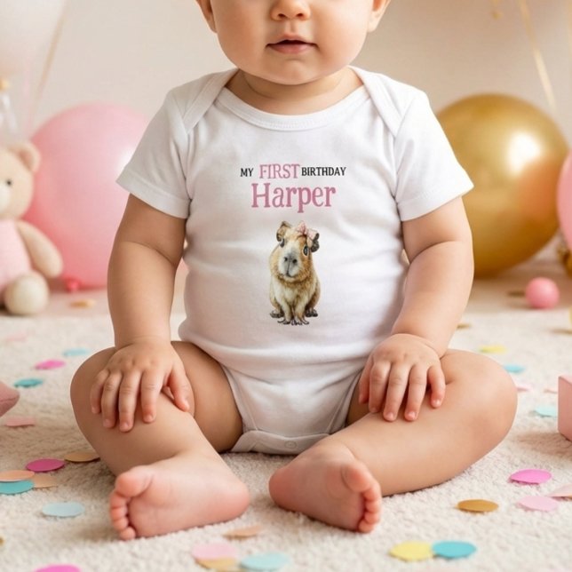 Body Para Bebê Capybara First Birthday • Birthday Outfit (baby wearing white bodysuit with cute capybara and pink first birthday name print on soft floor)