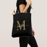 Bolsa Tote Elegante negro Dourado, personalizado, monograma<br><div class="desc">Negra Elegante Simples e Dourada Monograma, Nome Inicial Script de Assinatura Personalizado Tote Bag. Este design com seu primeiro nome em um estilo bonito, escrito à mão, estilo swash tail typografia (ou caligrafia) com monograma inicial em ouro e branco em preto. presente feminina excelente para aniversário, casamento, Natal, doce festa...</div>