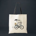 Bolsa Tote Peanuts | Snoopy & Woodstock Bicycle<br><div class="desc">Pedal into style and classic charm with this adorable cream canvas tote bag, featuring Snoopy and Woodstock on a bicycle! This fun tote showcases a delightful line-art illustration of Snoopy, wearing sunglasses, happily riding a vintage-style blue bicycle with Woodstock perched safely behind him. The dashed lines behind the back wheel...</div>
