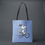 Bolsa Tote Peanuts | Snoopy & Woodstock Bicycle<br><div class="desc">Pedal into style and classic charm with this adorable cream canvas tote bag, featuring Snoopy and Woodstock on a bicycle! This fun tote showcases a delightful line-art illustration of Snoopy, wearing sunglasses, happily riding a vintage-style blue bicycle with Woodstock perched safely behind him. The dashed lines behind the back wheel...</div>