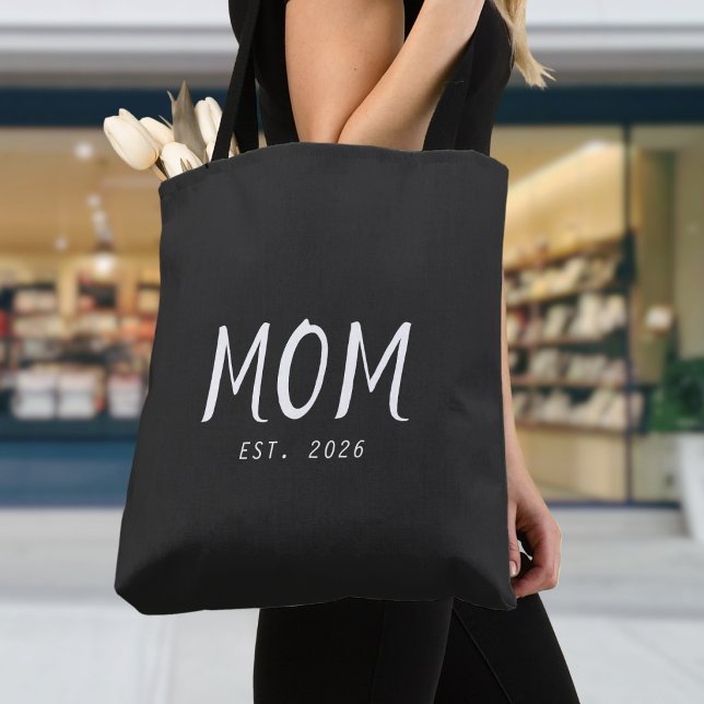 Bolsa Tote Presente de Mãe Estabelecida Nova Mãe (A black tote bag with customizable white text saying "Mom Est. 2026"
)