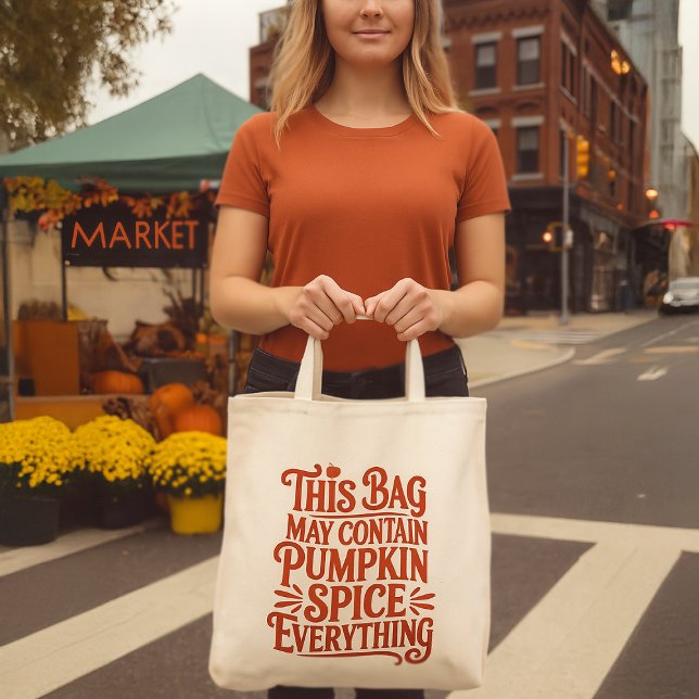 Bolsa Tote Pumpkin Spice Everything Funny Fall Warning Label (woman holding a funny pumpkin spice grocery tote bag in front of an urban market stall)