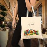 Bolsa Tote Script de nome de aves de papagaio<br><div class="desc">Aves tropicais,  papagaios em azul,  amarelo e vermelho sentados em folhas verdes de palma. Decorado com flores tropicais. Sem cor de fundo. Modelo para um nome,  script de estilo com letra preta.</div>