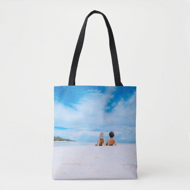 Bolsa Tote Two women lying on white sand facing beach under b (Frente)