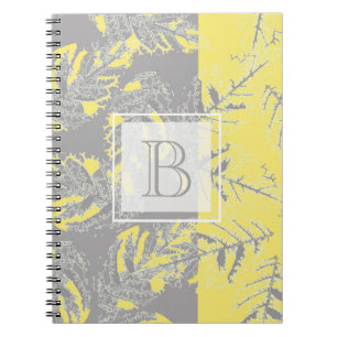 Caderno Espiral Cinzas e folhas amarelas sobre fundo listrado.