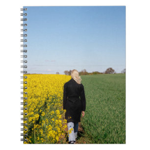 Caderno Espiral Mulher em casaco preto em pé sobre grama verde 