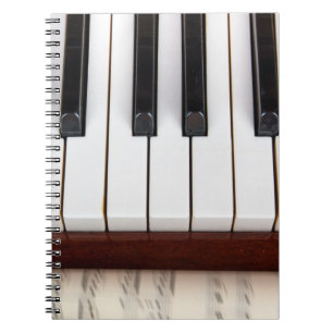Caderno Espiral notas musicais sobre o fundo de uma pianoacústica