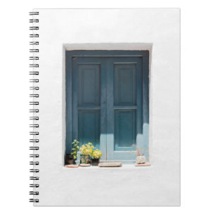 CADERNO ESPIRAL PORTA DE MADEIRA AZUL NA PAREDE CONCRETA BRANCA