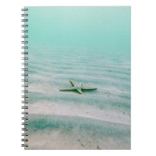 Caderno Espiral Starfish branco sobre areia submarina pela manhã