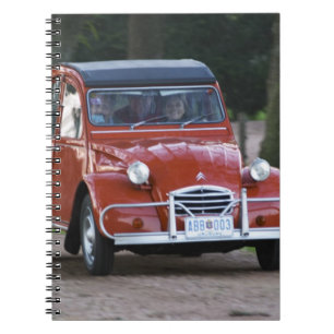 Caderno Espiral Um velho Citroen 2CV vermelho com uma mulher sorri