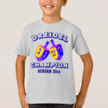 Camiseta Campeão engraçado colorido de Hanukkah Dreidels<br><div class="desc">Alguém na família é o CAMPEÃO de DREIDEL - conceda-os com esta camisa personalizada engraçada! O espaço por um nome e um ano opcional é fácil de personalizar; Dreidel e o campeão podem igualmente ser personalizados. A pia batismal aberta do estilo em azul escuro permite meu design original e extremamente...</div>