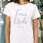 Camiseta Casamento de noiva de equipe personalizado azul em<br><div class="desc">Celebre o seu esquadrão noivo com esta t-shirt personalizada do casamento! As palavras 'Team Bride' são escritas em uma fonte de script de tendência e abaixo você pode adicionar um nome personalizado, data de casamento, local ou outro texto. Um presente adorável para um fim de semana de festa de solteira,...</div>