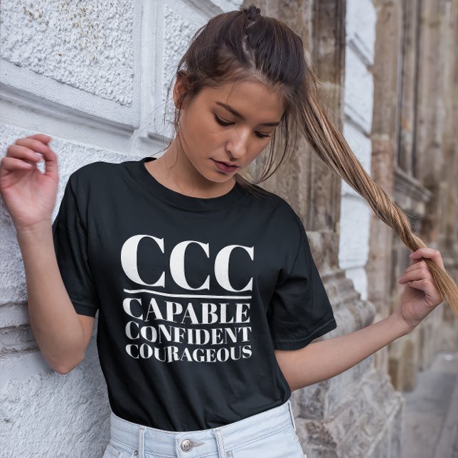 Camiseta CCC- Capaz, Confiante, Corajoso (Young woman wears a "CCC:Capable, Confident, Courageous" black t-shirt.)