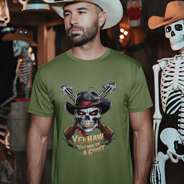 Camiseta Cowboy do crânio - Oeste selvagem assustado (A man wearing a fatigue green t-shirt with a skull cowboy design stands in a dimly lit room)