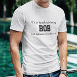 Camiseta É um trabalho difícil ser Bob<br><div class="desc">A Camisa Engraçada diz em letras negras,  "É um trabalho difícil ser BOB,  mas alguém tem que fazer isso". Personalize-o com o seu próprio nome ou personalize-o alterando as palavras. Faz um presente de Excelente! Vá em frente...  coloque um SMILE no rosto dele!</div>