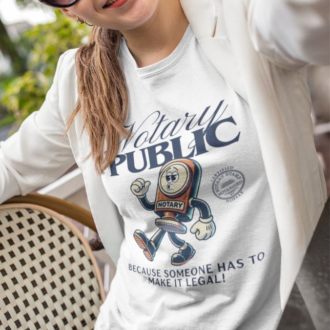 Camiseta Engraçado Notário Público - Humor Notório (Selfie of a woman wearing a funny notary public t-shirt with a cartoon stamp character)