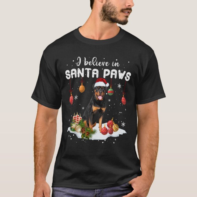 Camiseta Eu Acredito Em Papais noeis Patas Natal Rottweiler (Frente)