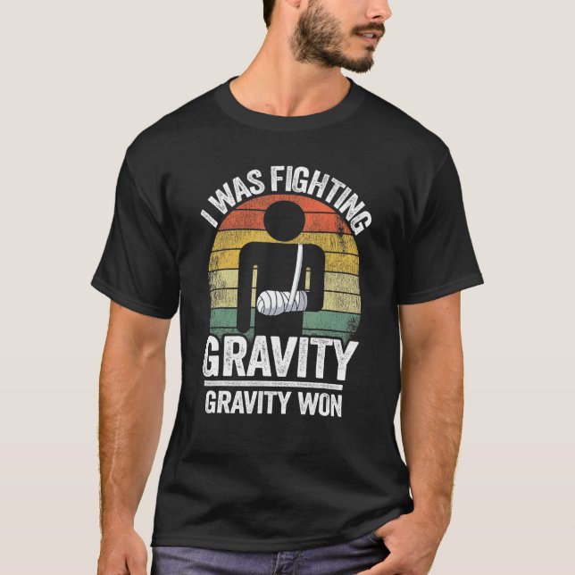 Camiseta Eu Estava Lutando Com Gravidade Ganhei Mão Quebrad (Frente)