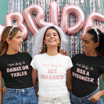 Camiseta Festa de solteira Mais Provável Para Casar<br><div class="desc">Traga um toque de antecipação divertida para as festividades da solteira com esta charmosa e personalizável design de camiseta! Apresentando a frase perfeitamente adequada "mais provável de CASAR-SE" em delicadas letras cor-de-rosa contra um fundo branco nítido, esta design é doce e indecente. É uma escolha ideal para a noiva ser...</div>
