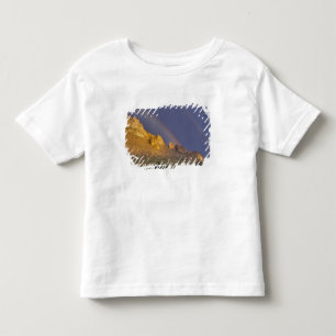 Camiseta Infantil Arco-íris duplo sobre uma formação rochosa perto d