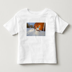 Camiseta Infantil Boneco de neve na frente do celeiro vermelho em