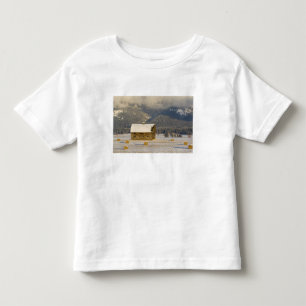 Camiseta Infantil Celeiro rústico e fardos de feno após uma neve fre