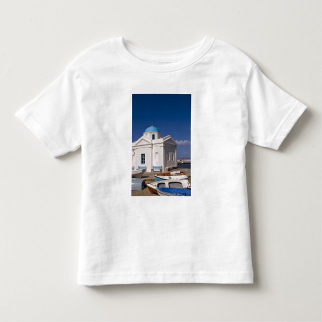Camiseta Infantil Igreja Branca na praia perto do Mar Egeu, em (Frente)