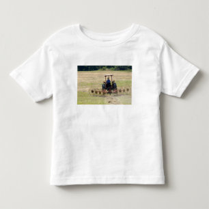Camiseta Infantil Um menino dirigindo uma colheita de trator