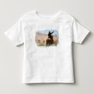 Camiseta Infantil Um vaqueiro trabalhando no rebanho em uma boiada