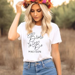 Camiseta Noiva para ser um casamento personalizado de Scrip<br><div class="desc">A camiseta de noivas de noiva feminina,  escrita em preto,  moderno e casual,  com script de caligrafia "Bride to Be" apresenta texto personalizado que pode ser personalizado com o nome próprio da noiva. Perfeito para a noiva vestir na festa de solteira e no fim de semana do casamento!</div>