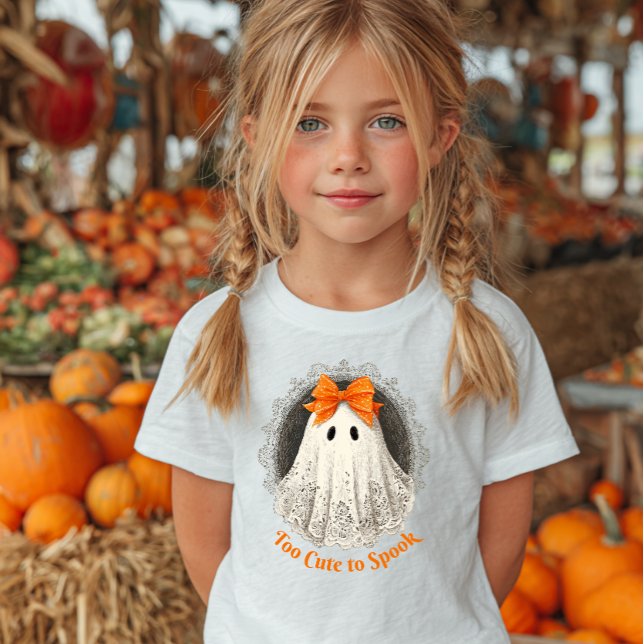 Camiseta Para Bebê Lace Ghost in Orange Bow Ornate Frame Design (Girl wearing a white shirt with a cute ghost illustration and "Too Cute to Spook.)