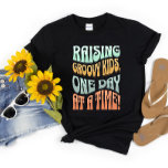 Camiseta Raising Groovy Kids Mom Life Retro Funny Cute<br><div class="desc">Show off your parenting skills with this stylish "Raising Groovy Kids, One Day at a Time!" retro t-shirt design. Perfect for any mom looking to add some vintage flair to her wardrobe while proudly showcasing her parenting style, this t-shirt is sure to become a favorite. Shop now for the latest...</div>