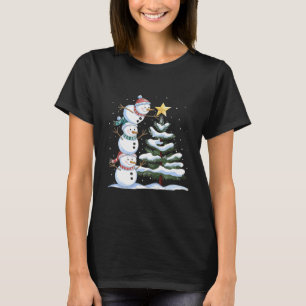 Camiseta Três bonecos de neve estão arranjando uma árvore d