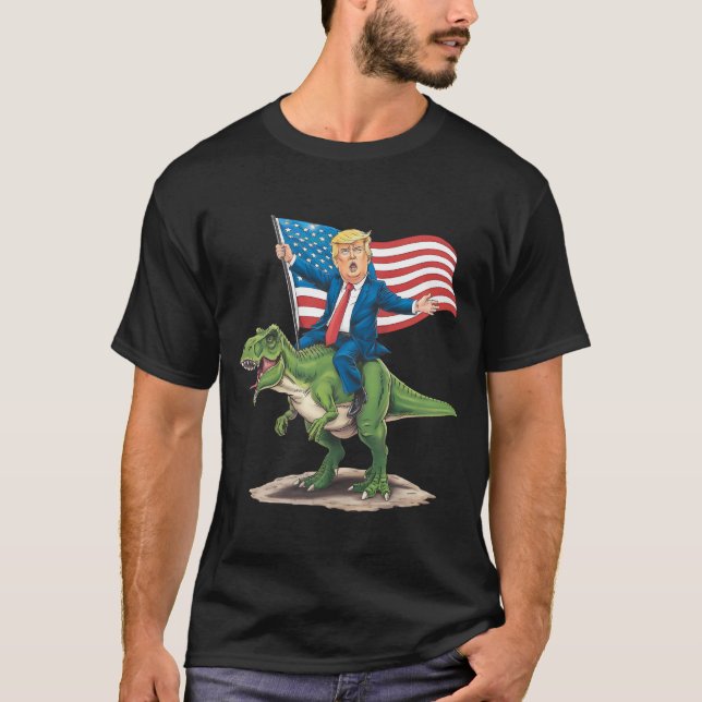 Camiseta Trump Riding Dinosaur T Rex USA Flag Americano (Frente)