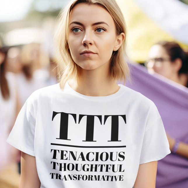 Camiseta TTT - Tenaz, Cuidadosa, Transformativa (Woman wears a "TTT: Tenacious, Thoughtful, Transformative" white t-shirt.)