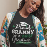 Camiseta Vovó Orgulhosa de 2023 formando verde-preto<br><div class="desc">Comemore a graduação do seu neto ou da sua neta com esta camiseta moderna que apresenta uma tipografia "Orgulhosa de um Formando 2023" em fontes negras e verdes decoradas com um boné formando preto com fita verde; personalize facilmente essa camiseta com o ano de graduação e o nome do formando...</div>
