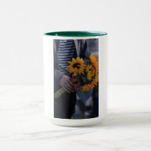 Caneca branca onde uma mão segura girassóis com AJ