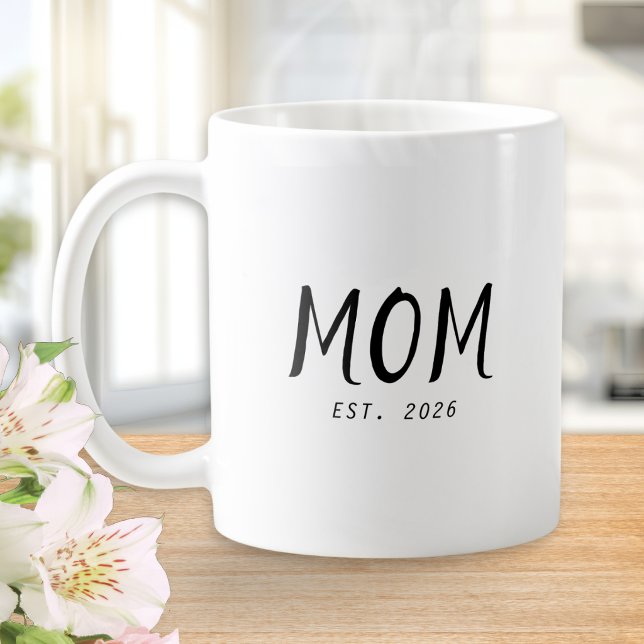 Caneca de Café de Presente para Mãe Estabelecida N (A white coffee mug with customizable words "Mom Est. 2026" in black text)
